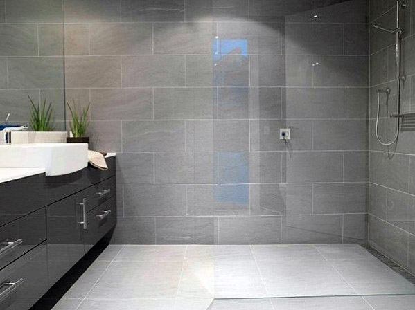 Modern bathroom with grey tiles, large mirror, lush plants, and a walk-in shower