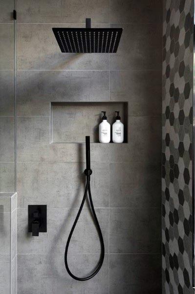 A contemporary bathroom design with matte black shower fixtures, grey wall tiles, and a built-in shelf for toiletries.