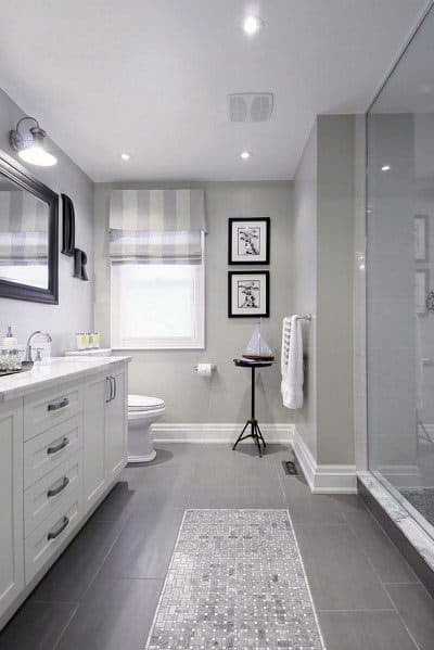 A modern bathroom with a sleek vanity, framed mirror, shower, and minimalistic decor in gray and white tones