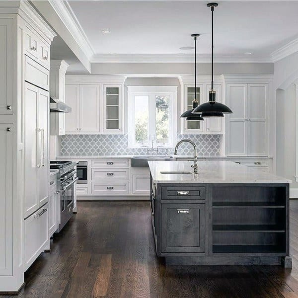 Light grey backsplash complements white cabinets and a dark island.