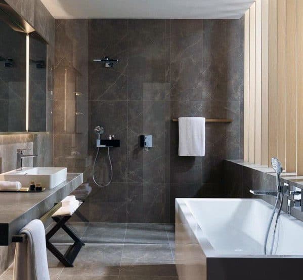 Modern bathroom with grey tiles, a shower, a bathtub, and a large mirror