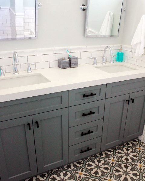 Bathroom with white beveled subway tile backsplash, grey vanity, and patterned floor tiles.