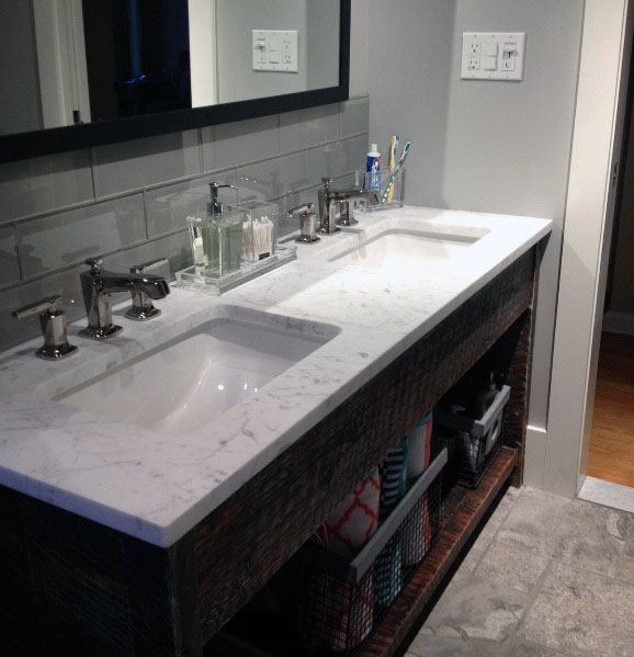 Bathroom with grey beveled subway tile backsplash, double sinks, and marble countertop.