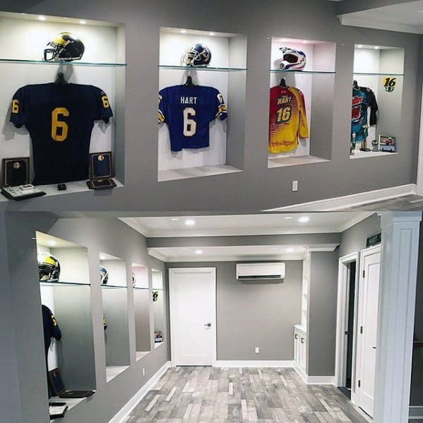 Minimalist sports-themed mancave with grey walls, framed jerseys in display cases, and wood-style flooring.