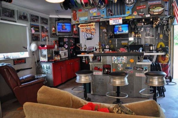 Garage bar with corrugated metal walls, hubcap stools, red cabinets, and sports-themed decor.