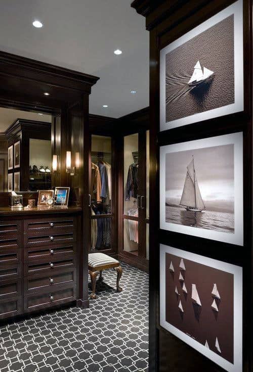 Elegant walk-in closet with dark wood, framed sailboat art, and a patterned carpet