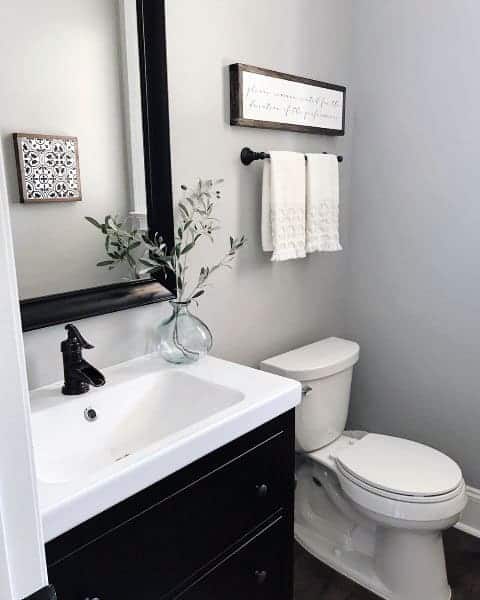 Minimalist half-bath with black vanity, framed mirror, and simple wall decor.