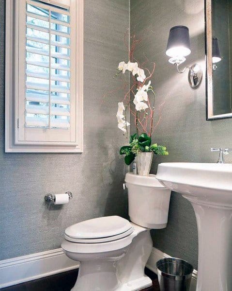 Modern bathroom with gray textured wallpaper, white fixtures, and orchid decor.