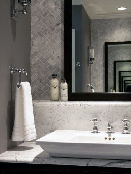 Bathroom with marble herringbone backsplash, chrome fixtures, and framed mirror.