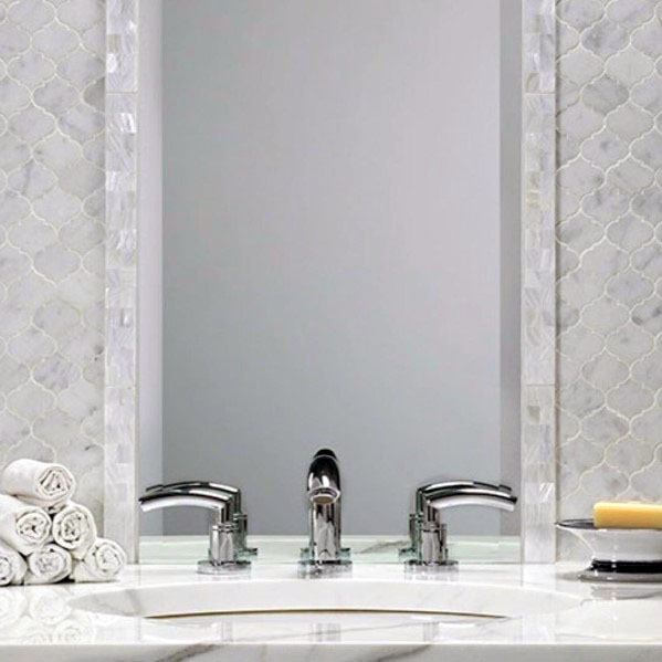 Bathroom with marble hexagon tile backsplash, chrome faucet, and framed mirror.