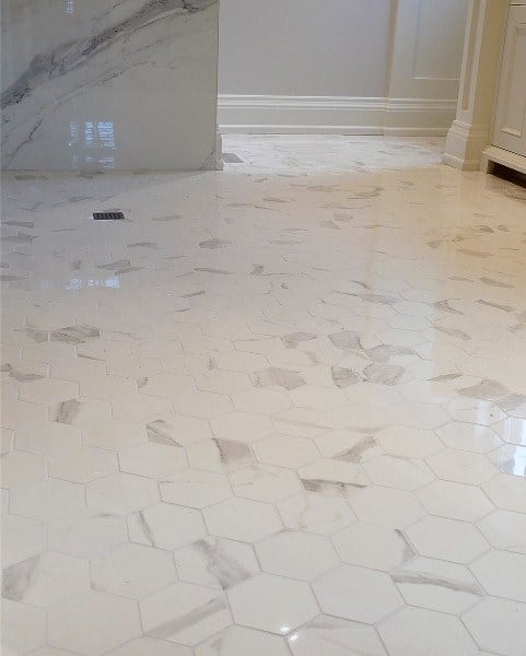 Bathroom with large white marble hexagonal floor tiles and subtle gray veining.