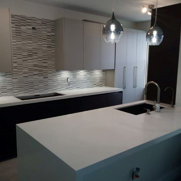 This modern kitchen features a textured backsplash that adds depth and complements the sleek cabinetry and lighting.