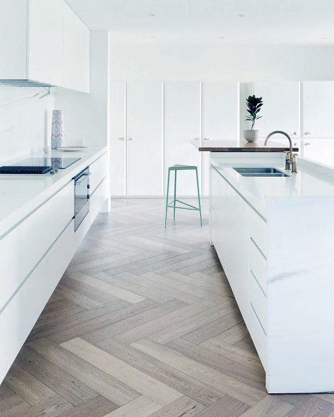 Modern kitchen with oak herringbone hardwood flooring, sleek white cabinetry, and minimalist design elements