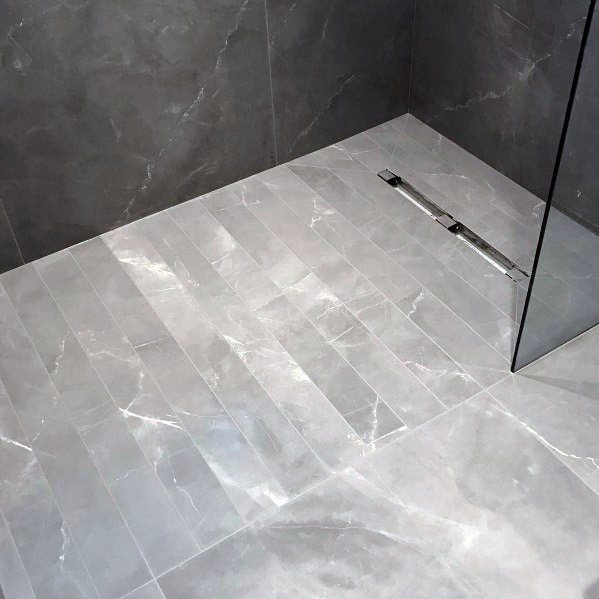 Sleek grey marble-tiled bathroom floor with a glass shower partition