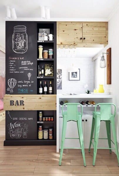 Creative home bar with chalkboard wall, wine storage, green bar stools, and wood accents.