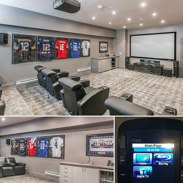 Home theater mancave with leather recliners, framed jerseys, large projector screen, and grey decor.