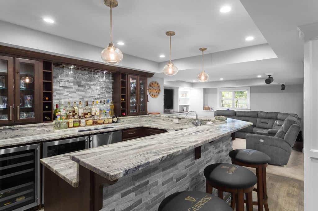 Spacious wet bar with granite countertops, stone backsplash, glass cabinets, and pendant lighting.