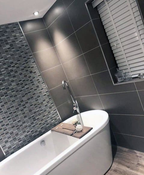 Modern bathroom with a grey freestanding tub, tiled wall, and window blinds