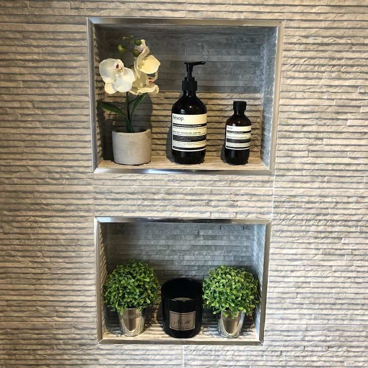 Recessed shower shelf with soap bottles, an orchid, and small decorative plants.