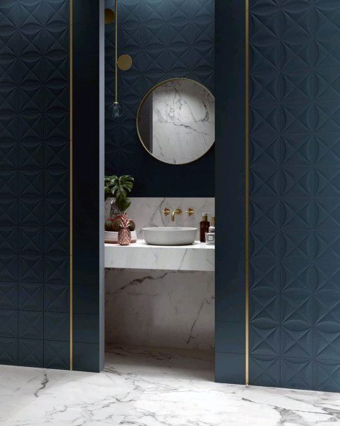 Modern bathroom with textured blue tiles, round mirror, and marble countertop.