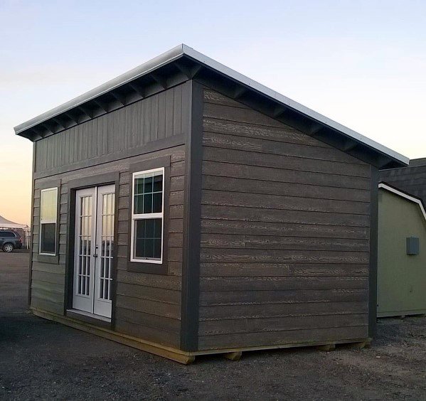 Modern wooden shed with French doors and large windows, featuring a sloped roof.