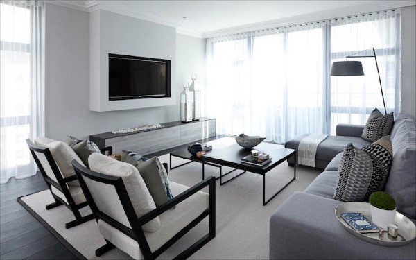 Contemporary living room with grey sectional, modern decor, and large windows with sheer curtains.