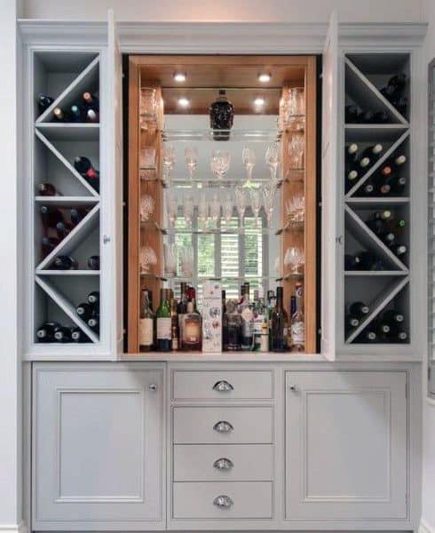 Sophisticated mini bar with gray cabinetry, built-in wine racks, mirrored interior, and glass display.