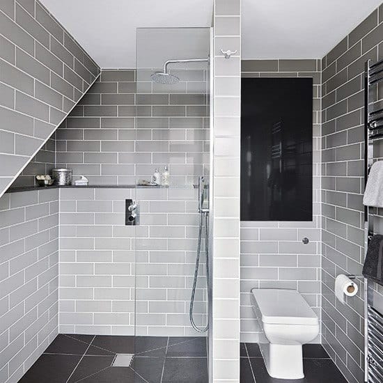 Modern bathroom with a glass shower, grey tiles, and a wall-mounted toilet