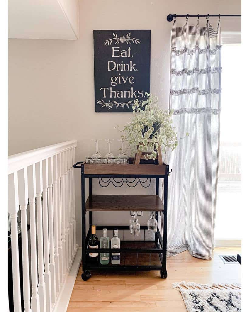 Bar cart with wine glasses, liquor bottles, and a motivational "Eat. Drink. give Thanks." sign above.