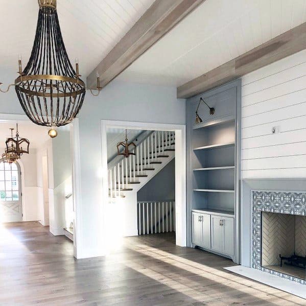 A farmhouse-inspired living room featuring a fireplace with intricate patterned tiles and built-in shelving.