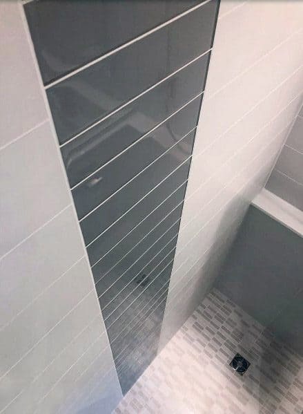 Bathroom corner with light grey tiles and a dark grey accent strip running vertically