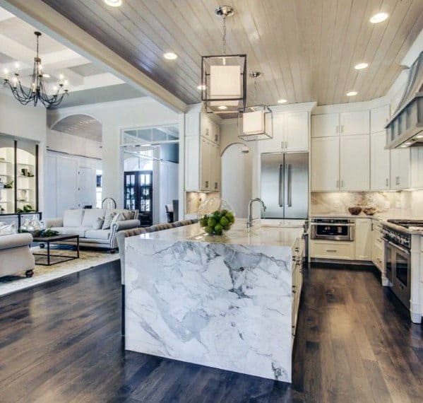 Elegant kitchen with dark hardwood flooring, marble island countertop, white cabinetry, and modern light fixtures, creating a sophisticated open space