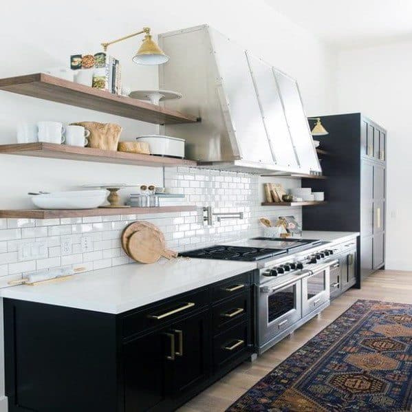 Modern black kitchen with open shelves, subway tiles, and a sleek white countertop.