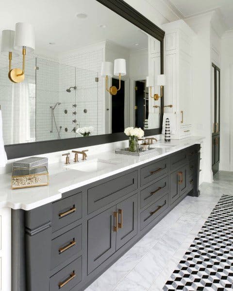 Modern bathroom with black vanity, large mirror, gold accents, and geometric tile flooring