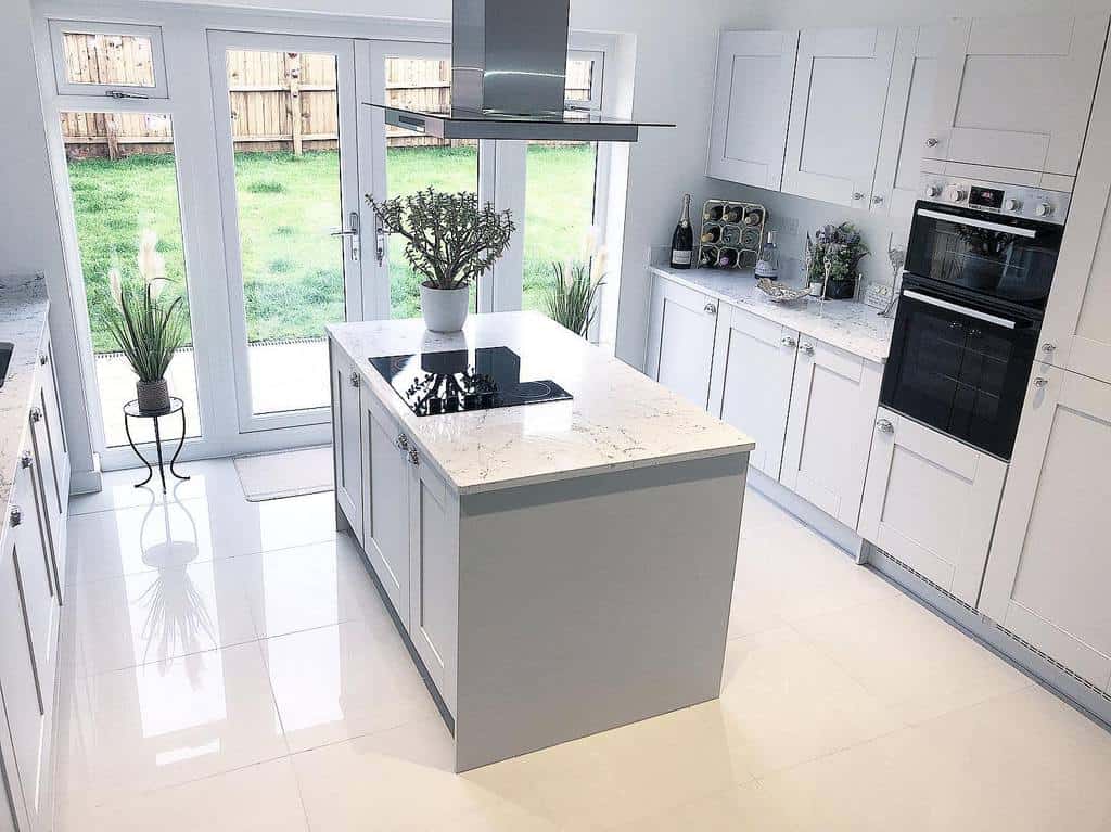 modern kitchen with white cabinets gray island marble countertops white tile flooring 