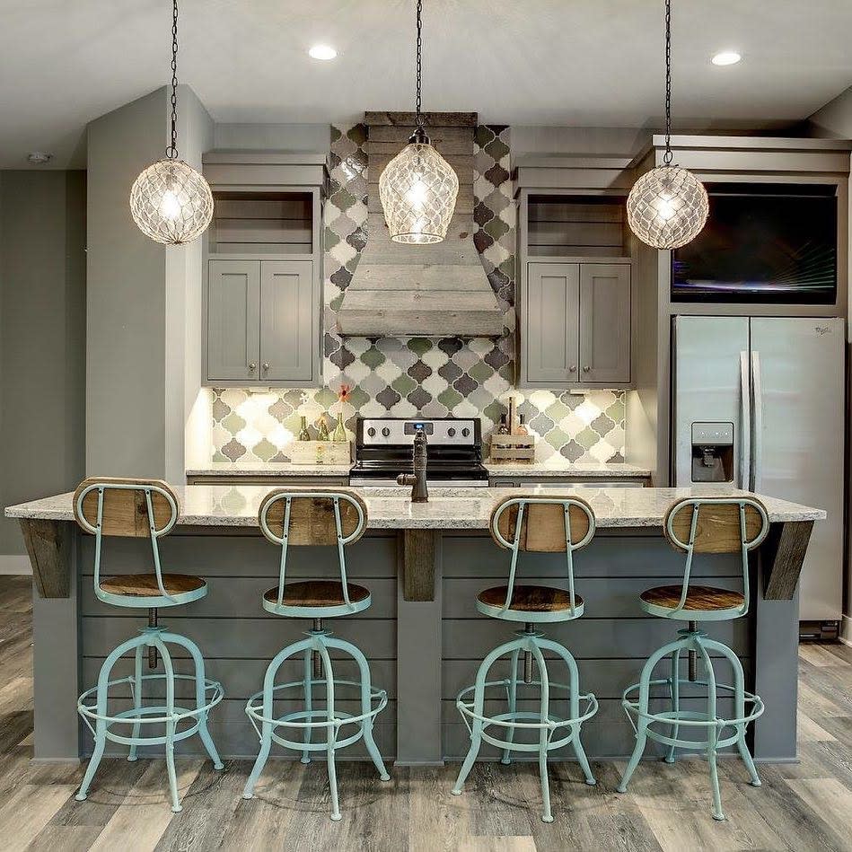 Basement kitchen with rustic island, decorative tile backsplash, and vintage bar stools.