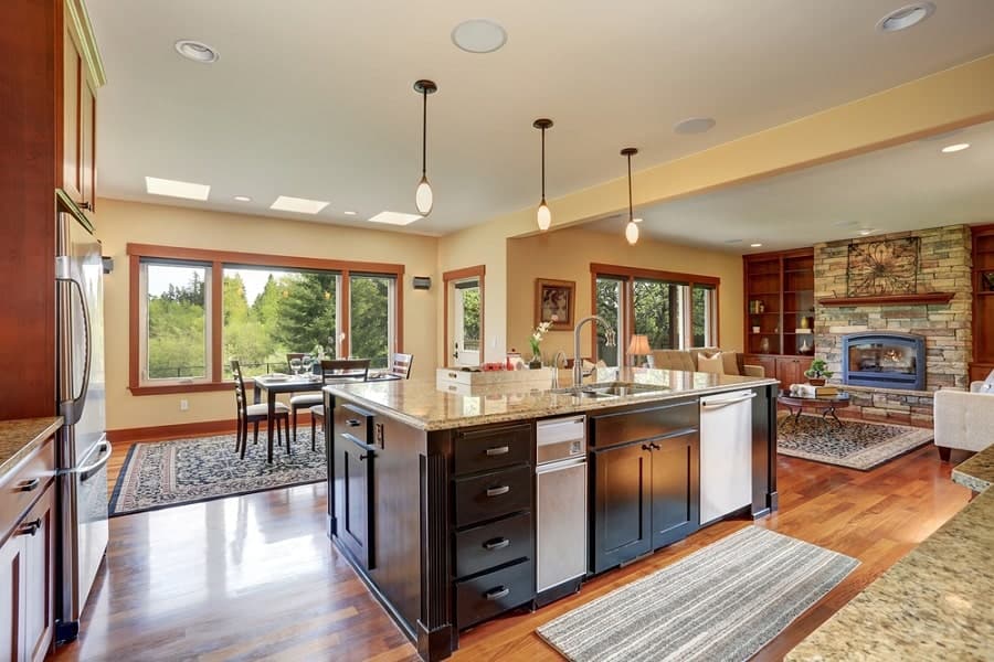 Spacious kitchen and living area with large windows, an island centerpiece, cozy fireplace, and wood accents throughout