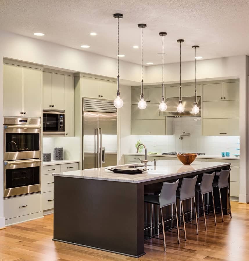 Modern kitchen with pendant lights, island seating, stainless steel appliances, and sleek wooden flooring