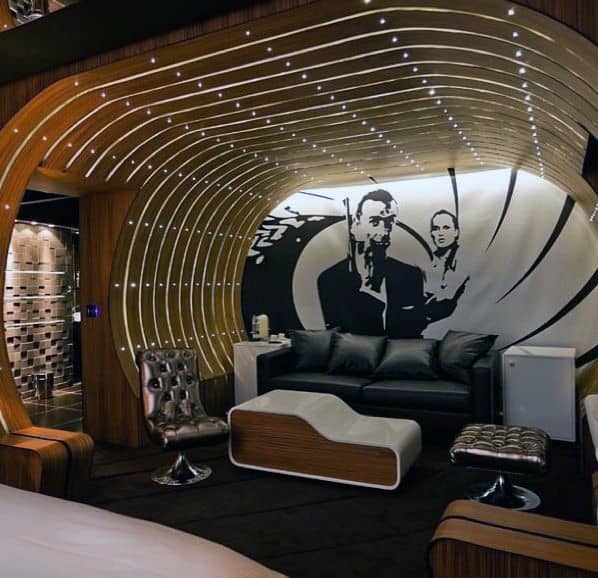 James Bond-themed man cave with curved wooden accents, black leather seating, and iconic wall art.