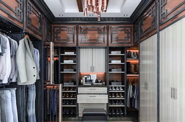 Luxurious walk-in closet with clothes, shoes, and a central dresser under an elegant light fixture