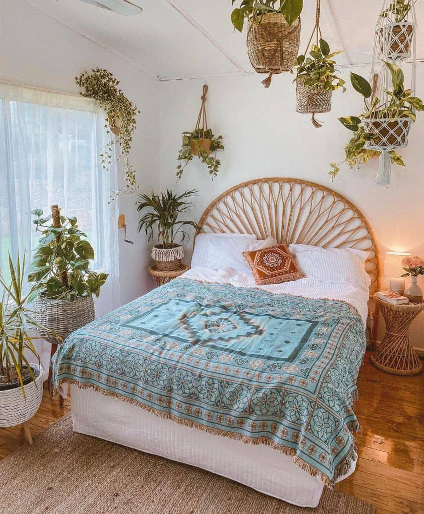 Boho bedroom with rattan headboard, hanging plants, earthy tones, and patterned turquoise bedding.