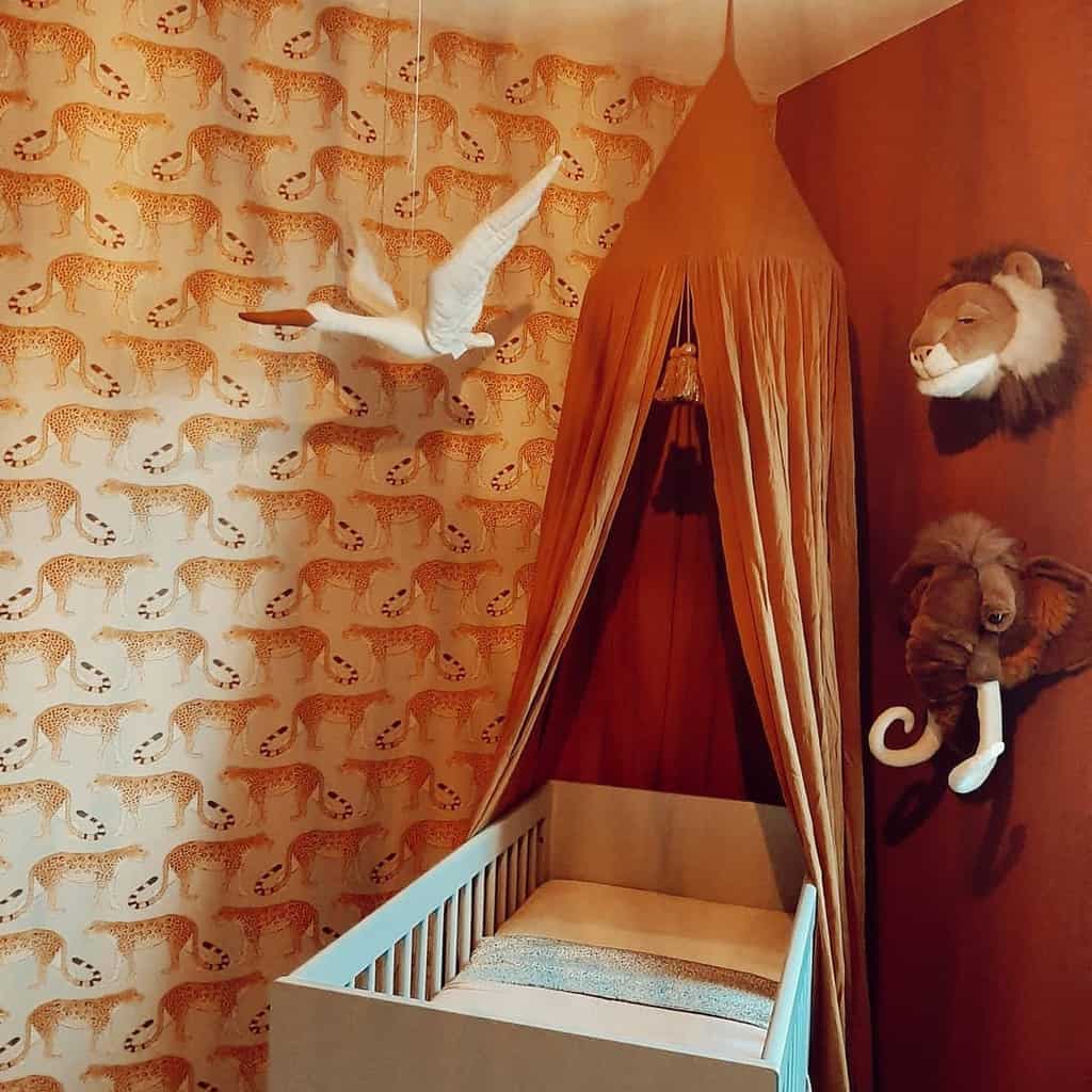 Baby room with tiger wallpaper, orange canopy, white crib, and animal wall decor.