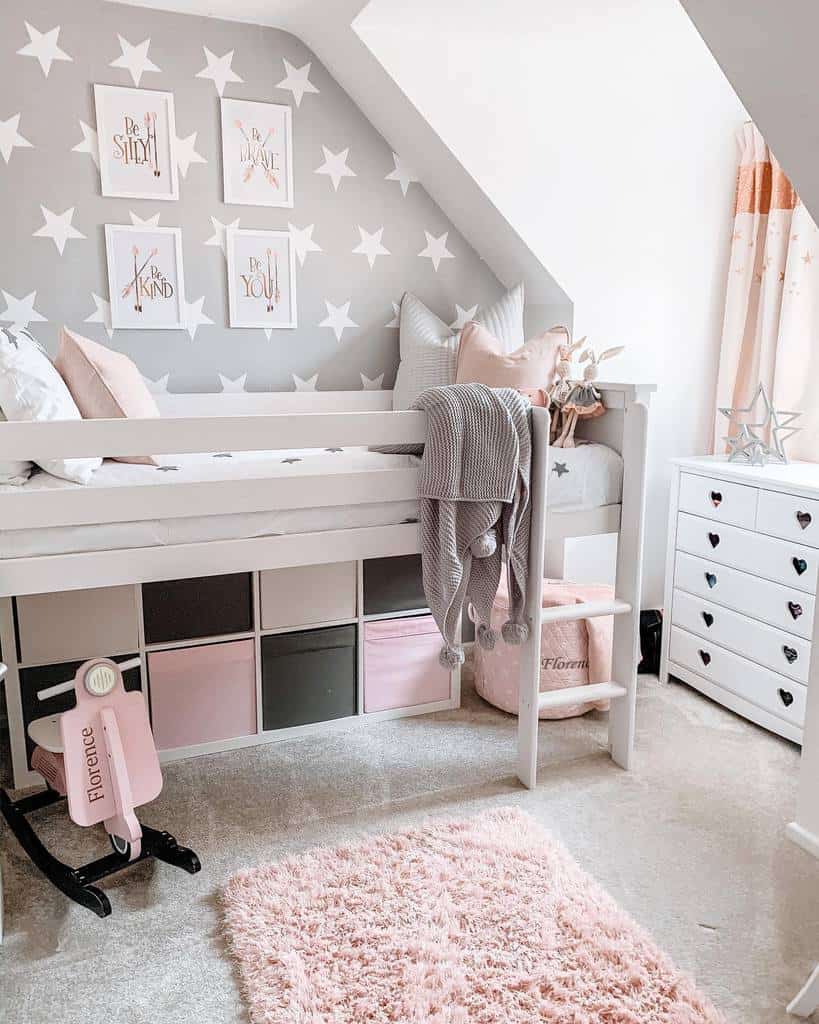 Kids' bedroom with star wallpaper, under-bed storage, white cabinet, and pink accents.