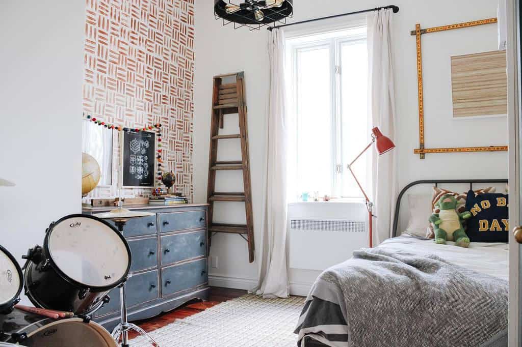 Kids' bedroom with striped wallpaper, drum kit, wooden ladder, and colorful wall art.