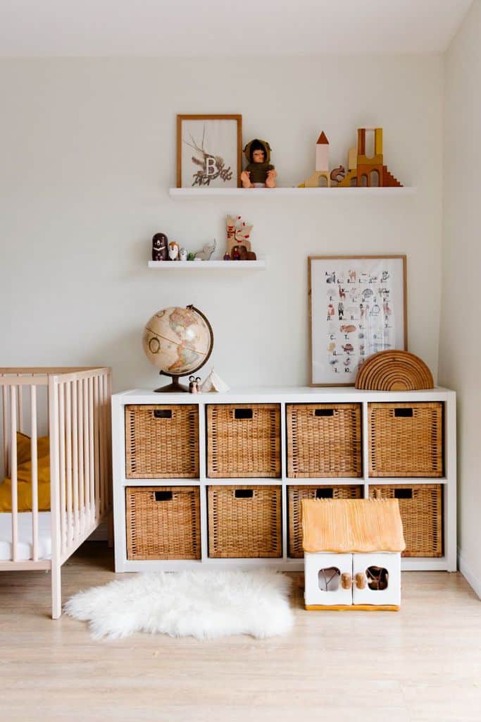 Kids' room with wicker basket storage, wooden crib, and decorative shelves.