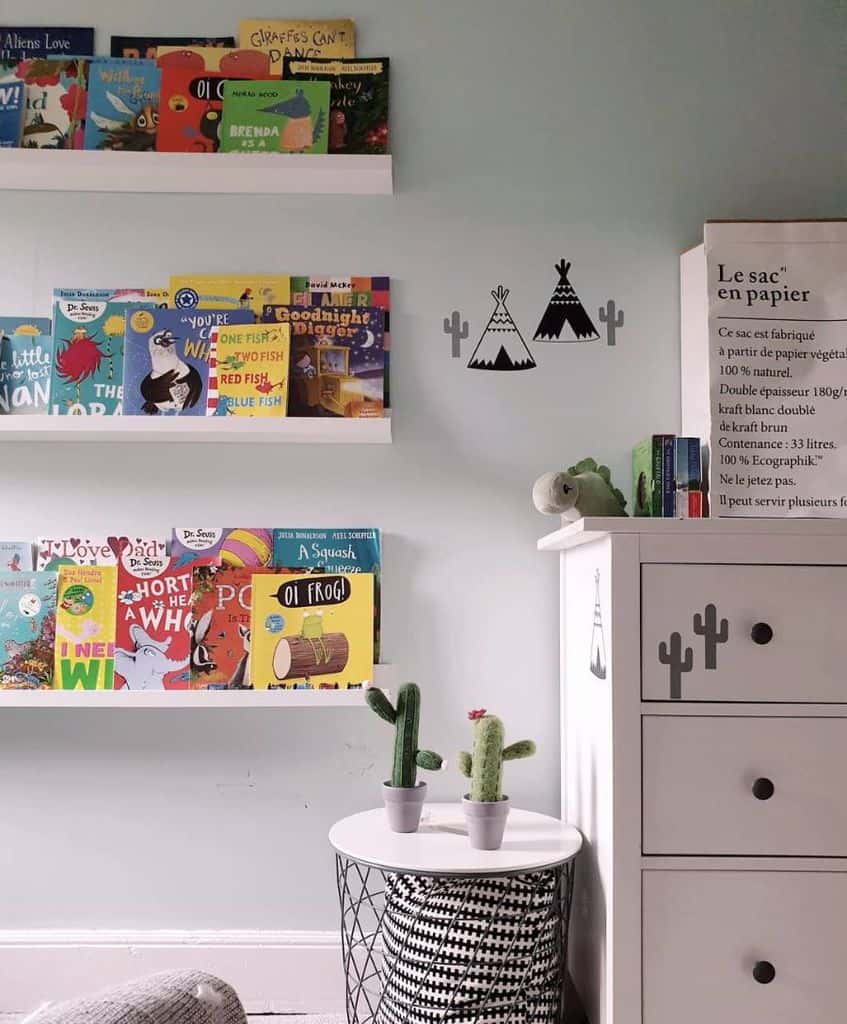 Kids' room with wall-mounted book shelves, cactus decor, and white dresser.