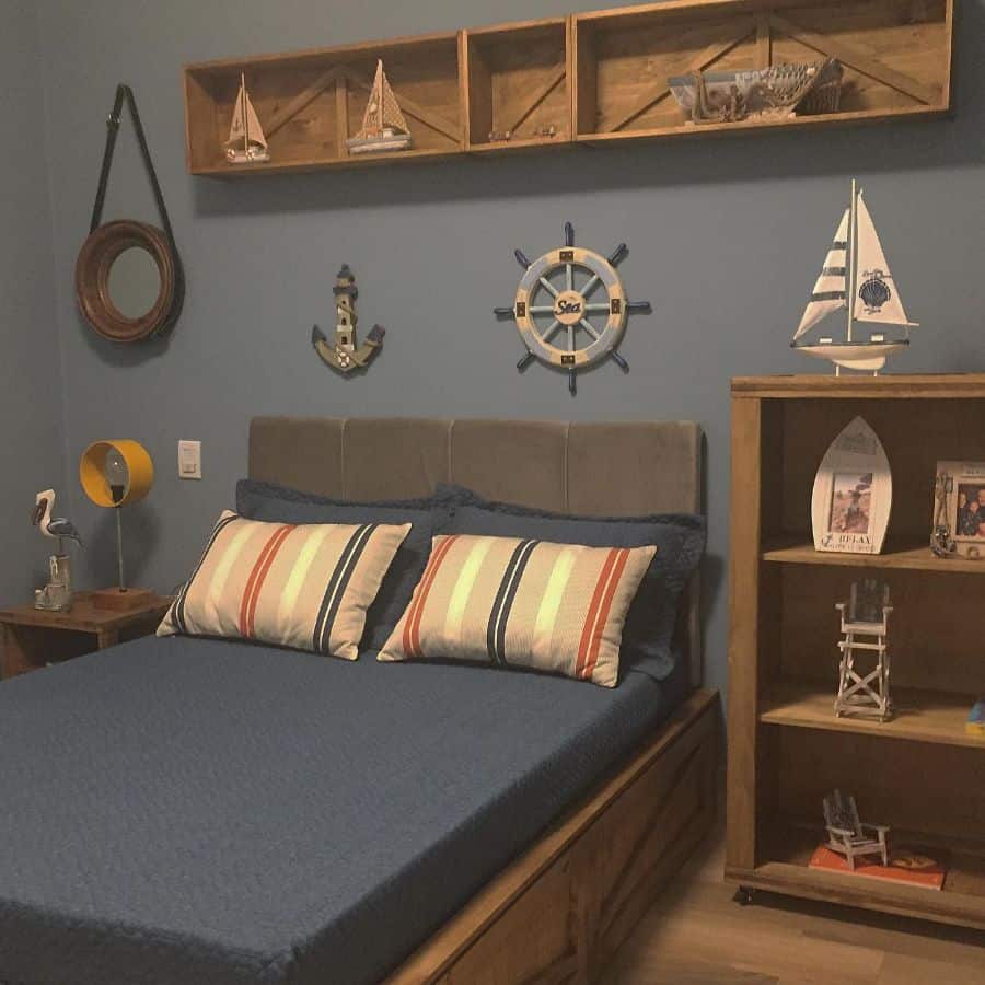 Marine-themed boys' bedroom with blue walls, nautical decor, and wooden shelves.