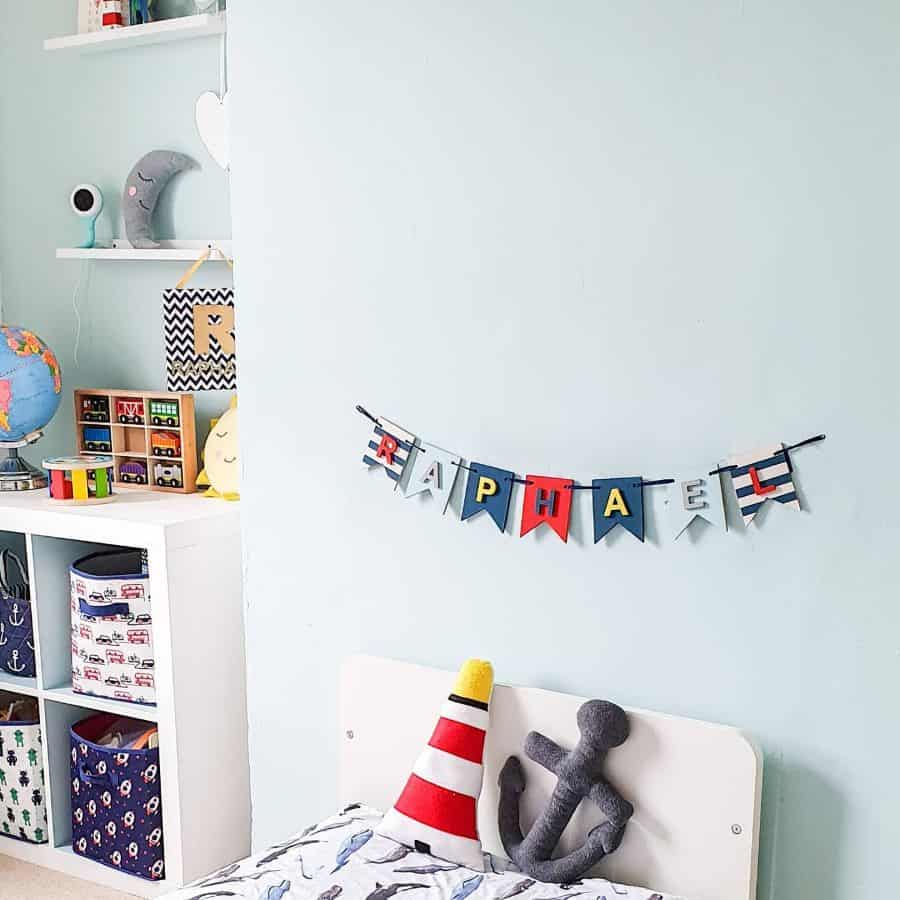 Kids' bedroom with blue walls, name banner, and colorful storage bins.