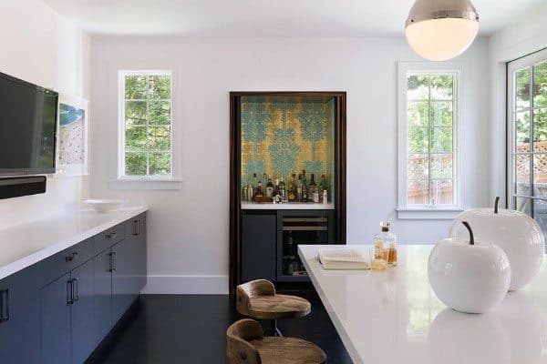 Built-in kitchen mini bar with patterned backsplash, beverage fridge, and sleek white countertop.