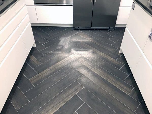 Contemporary kitchen with sleek white cabinetry and dark herringbone tile flooring, creating a stylish and modern design